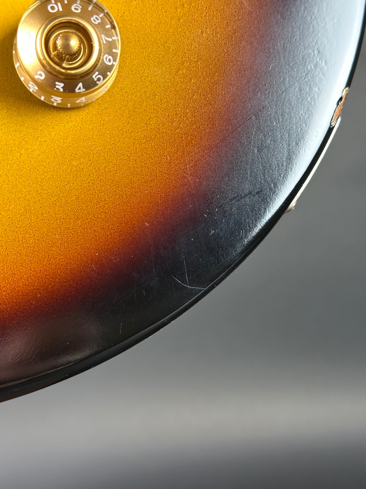 Close-up of a guitar's sunburst finish with a gold tuning peg.