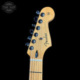 Close-up of a Fender Telecaster electric guitar headstock in natural maple wood, featuring six black tuning pegs and the Fender script logo, set against a solid black background.