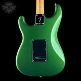 The back of a green Fender electric guitar, featuring a metallic green body, maple neck, black pickguard, and a Fender logo plate on a black background.