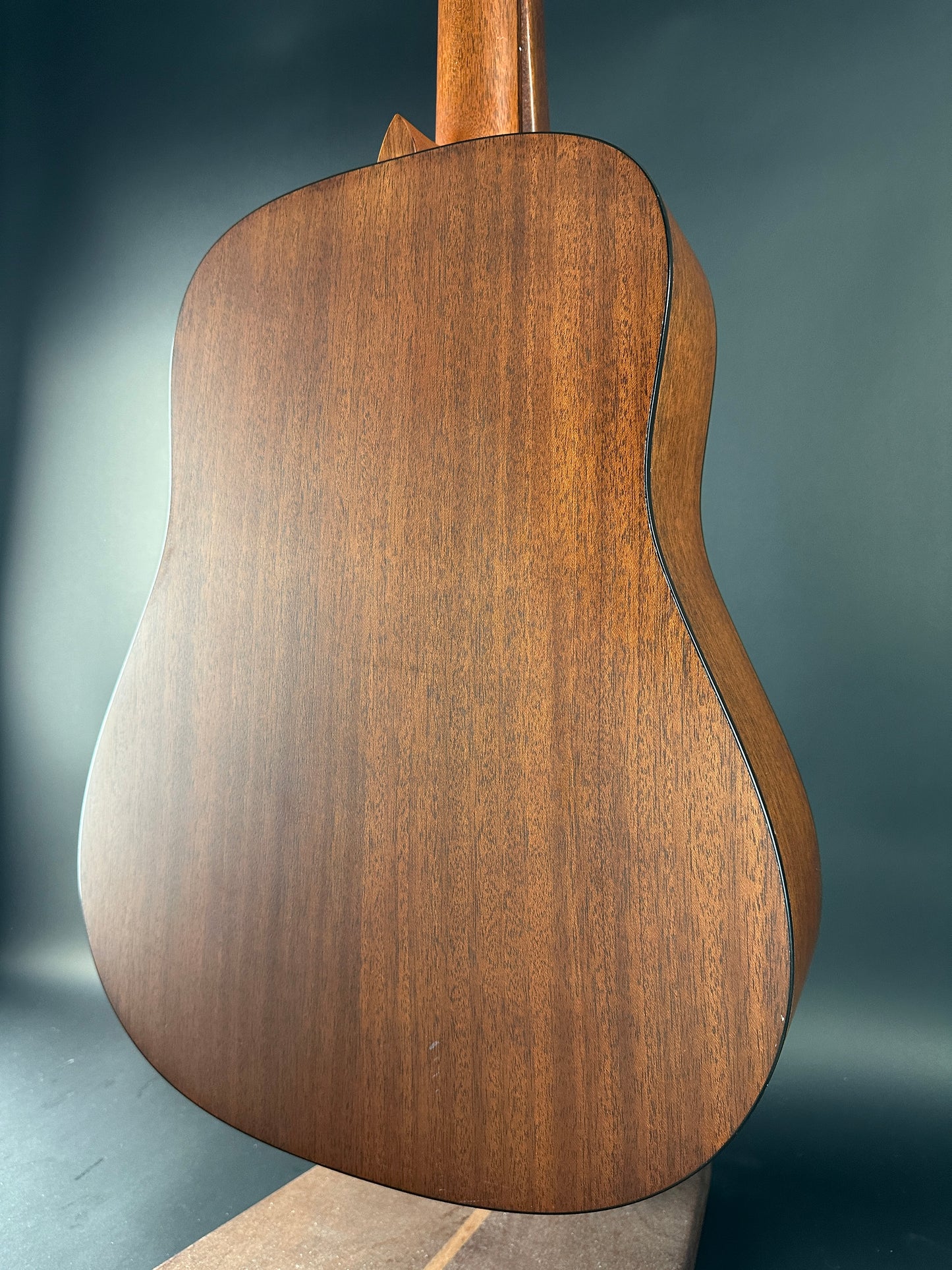 Close-up of a wooden acoustic guitar body on a dark background