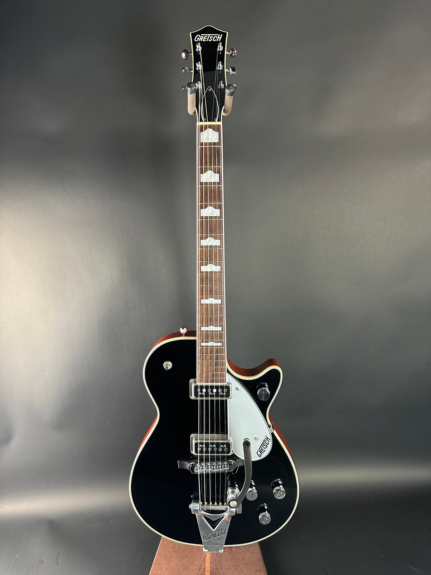 Black electric guitar on a gray background