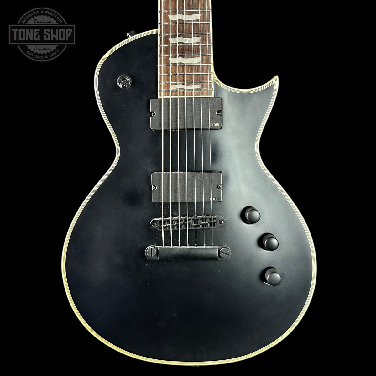 Black electric guitar with a visible brand logo on a black background