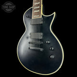 Black electric guitar with a 'Tone Shop' logo in the corner