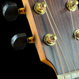 Close-up of a guitar headstock with tuning pegs on a black background
