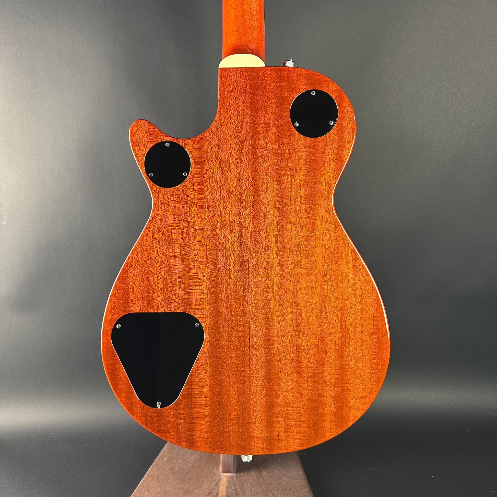 Back view of a wooden electric guitar with a dark gray background