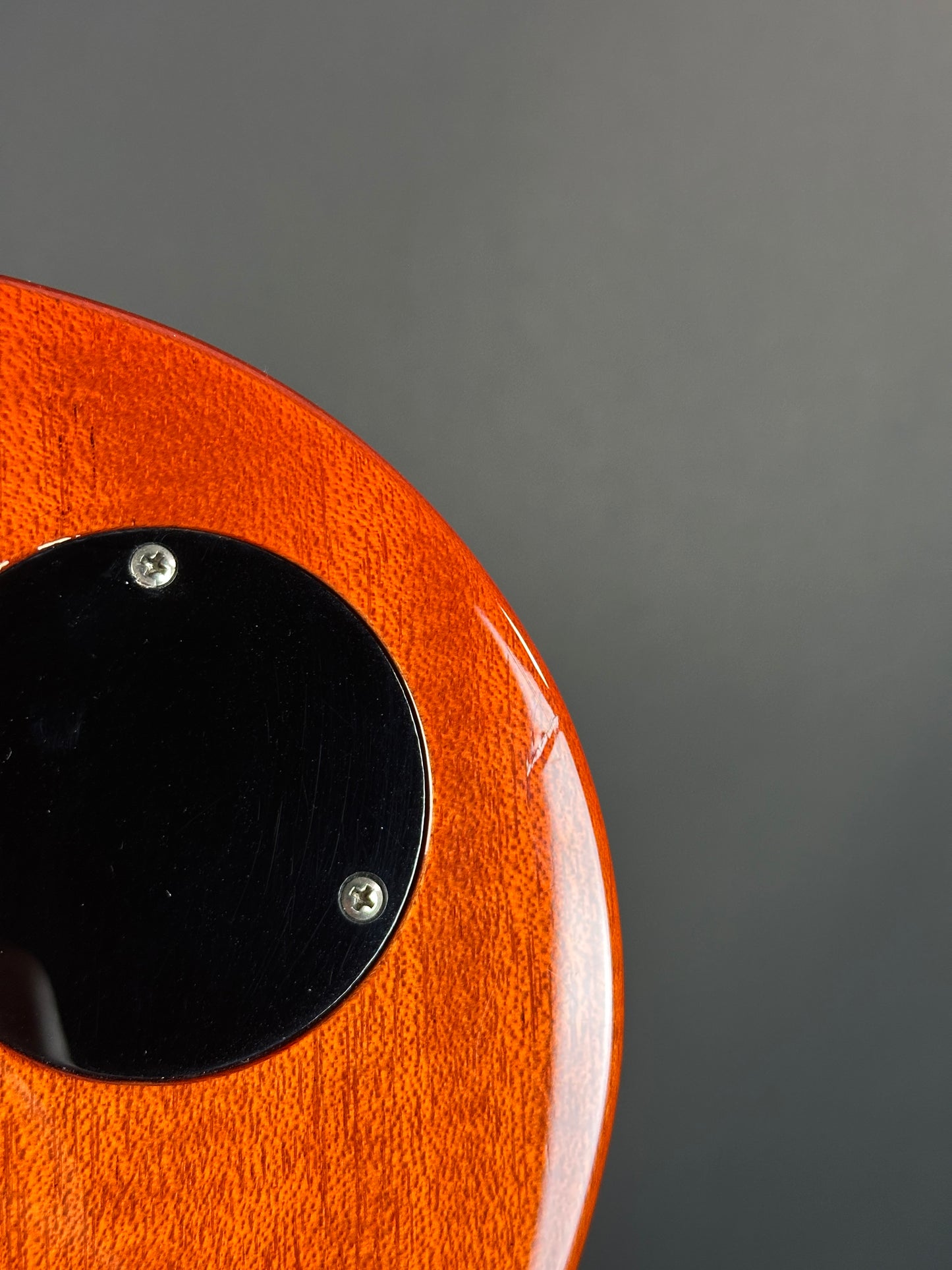 Close-up of an orange object with a black circular component on a gray background