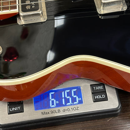 Digital scale displaying weight of a guitar, with a close-up view of the scale and guitar.