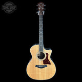 Acoustic guitar with a cutaway on a black background, featuring the Taylor logo.
