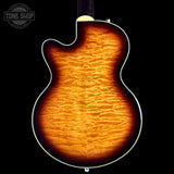 The back of an electric guitar with a vibrant flame maple top, showing a rich sunburst gradient from bright orange to dark brown, set against a solid black background.