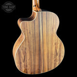 Close-up of a wooden acoustic guitar body with 'Tone Shop' branding.