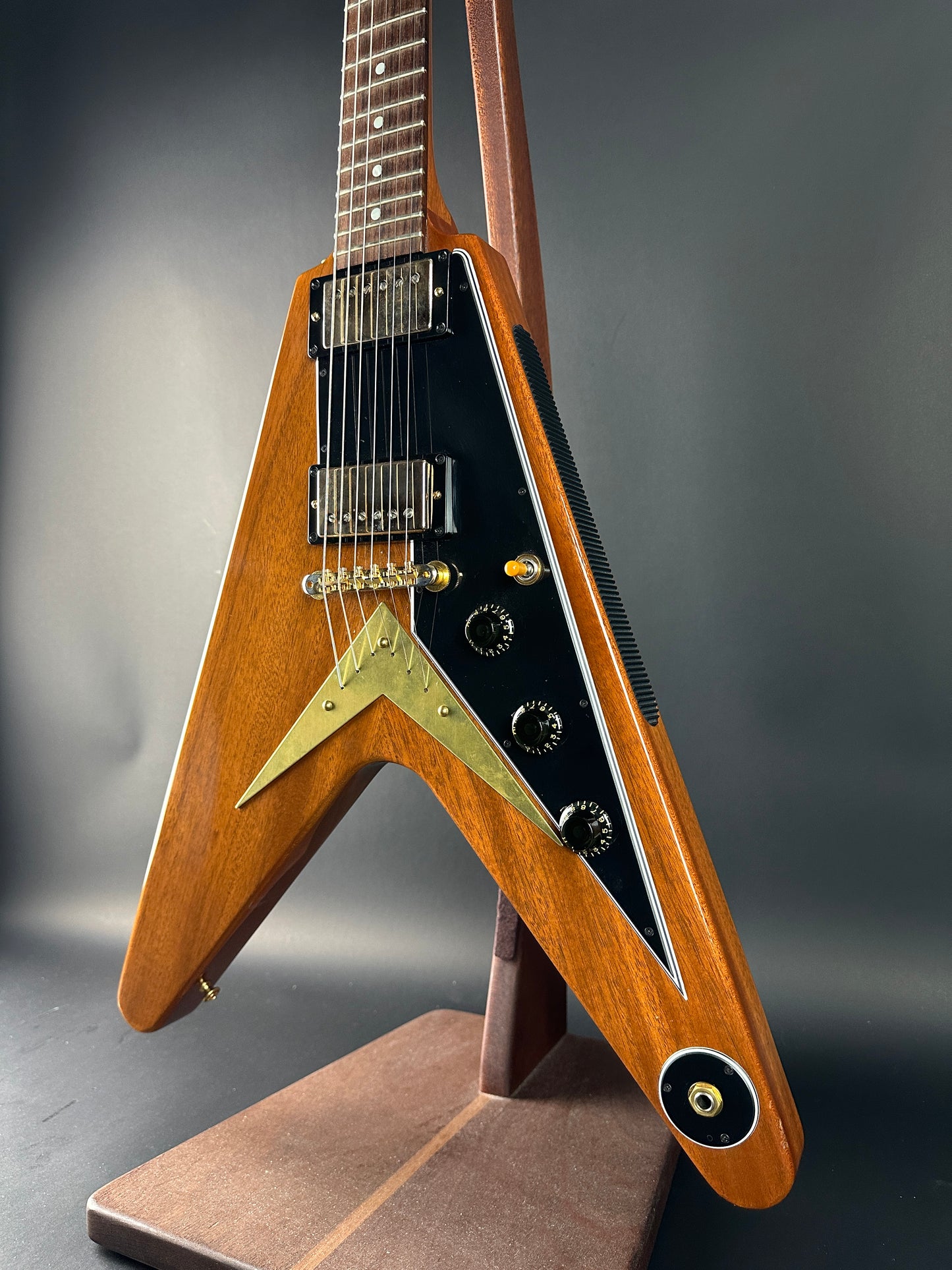 Close-up of a wooden electric guitar with a metallic finish on a dark background