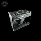 A black guitar amplifier with an open front panel, showing the internal speaker and wiring, photographed against a solid black background. A Tone Shop watermark is visible in the top-left corner.