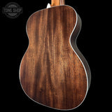 Close-up of a wooden acoustic guitar back with 'Tone Shop' logo.