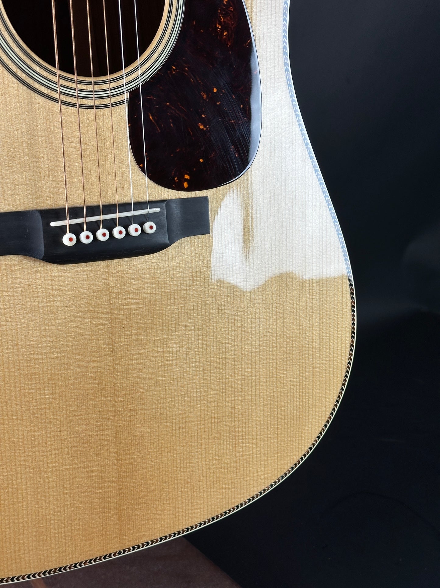 Close-up of an acoustic guitar's body and headstock on a black background