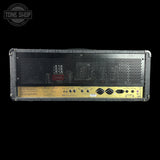 A Marshall amplifier head photographed from the back against a solid black background. The unit features a textured gray speaker grille, a gold-colored lower control panel with various knobs and jacks, and a circular Tone Shop watermark in the top-left corner.