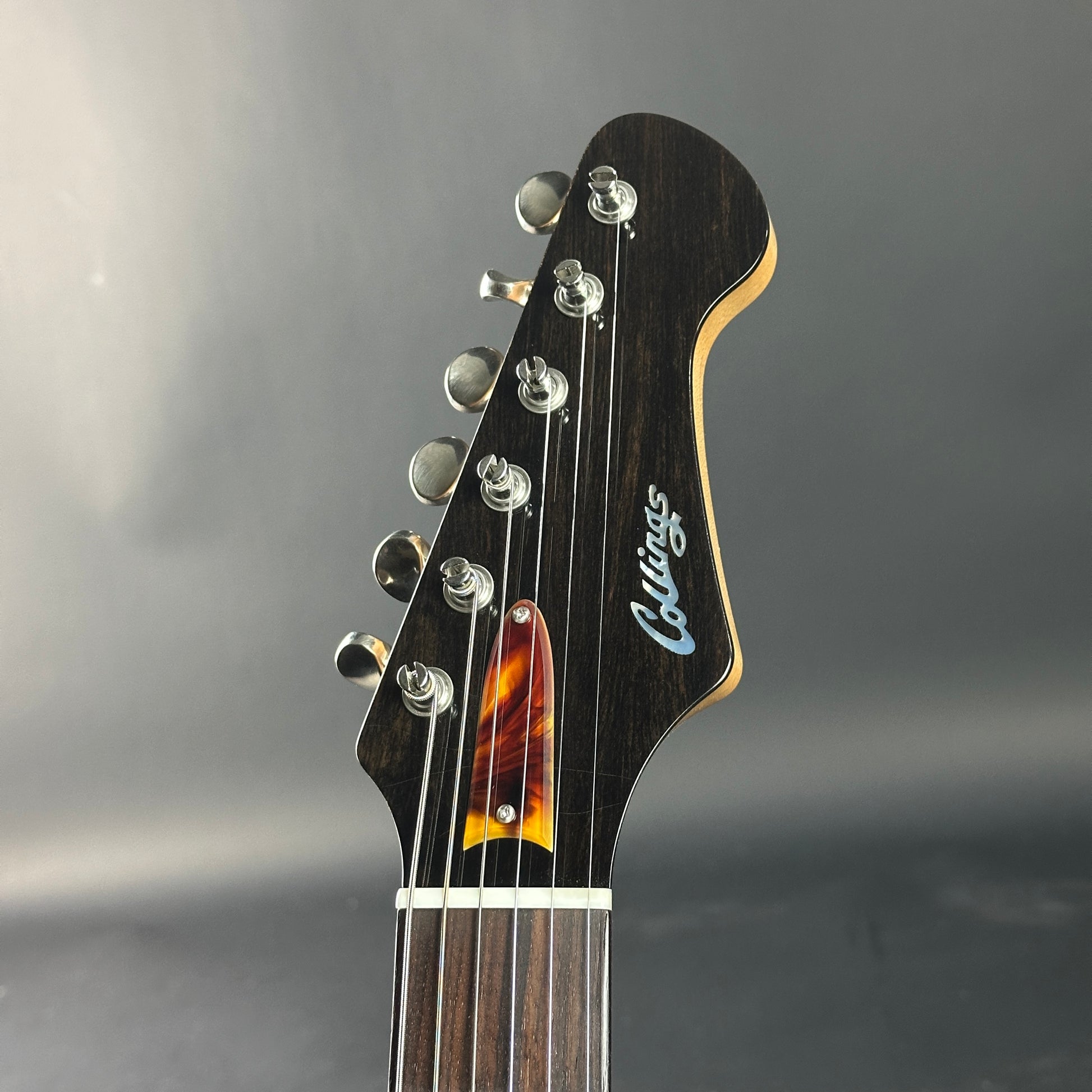 Collings guitar headstock with tortoiseshell inlay on a gray background