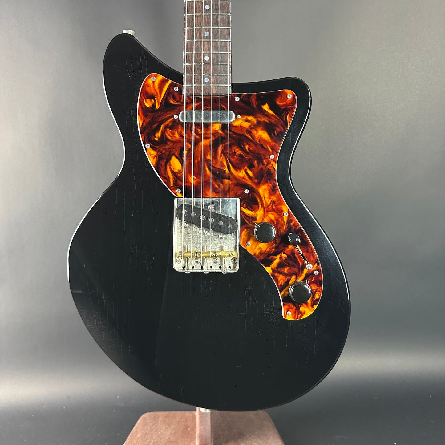 Black electric guitar with flame-patterned body on a gray background