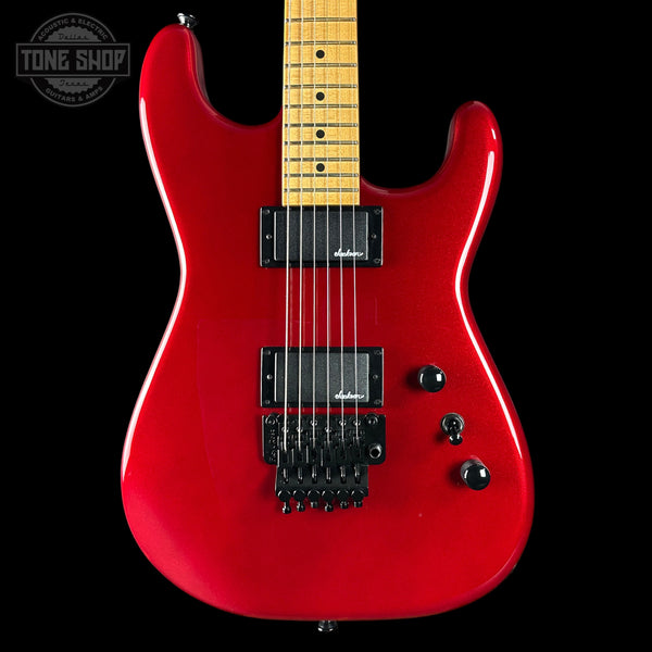 Red electric guitar with a black pickguard on a black background, featuring the Tone Shop logo.