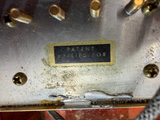 Close-up of a worn metal surface with multiple brass screws and a small rectangular black label reading 'PAYENY APPLIED FOR'.