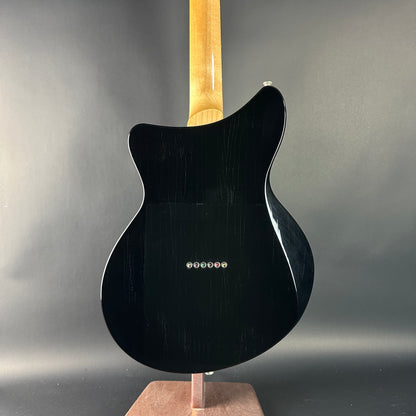 Black electric guitar on a stand against a gray background