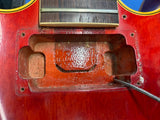 Close-up of the lower body of a red electric guitar, showing the soundhole, bridge area, and part of the cable entry point.