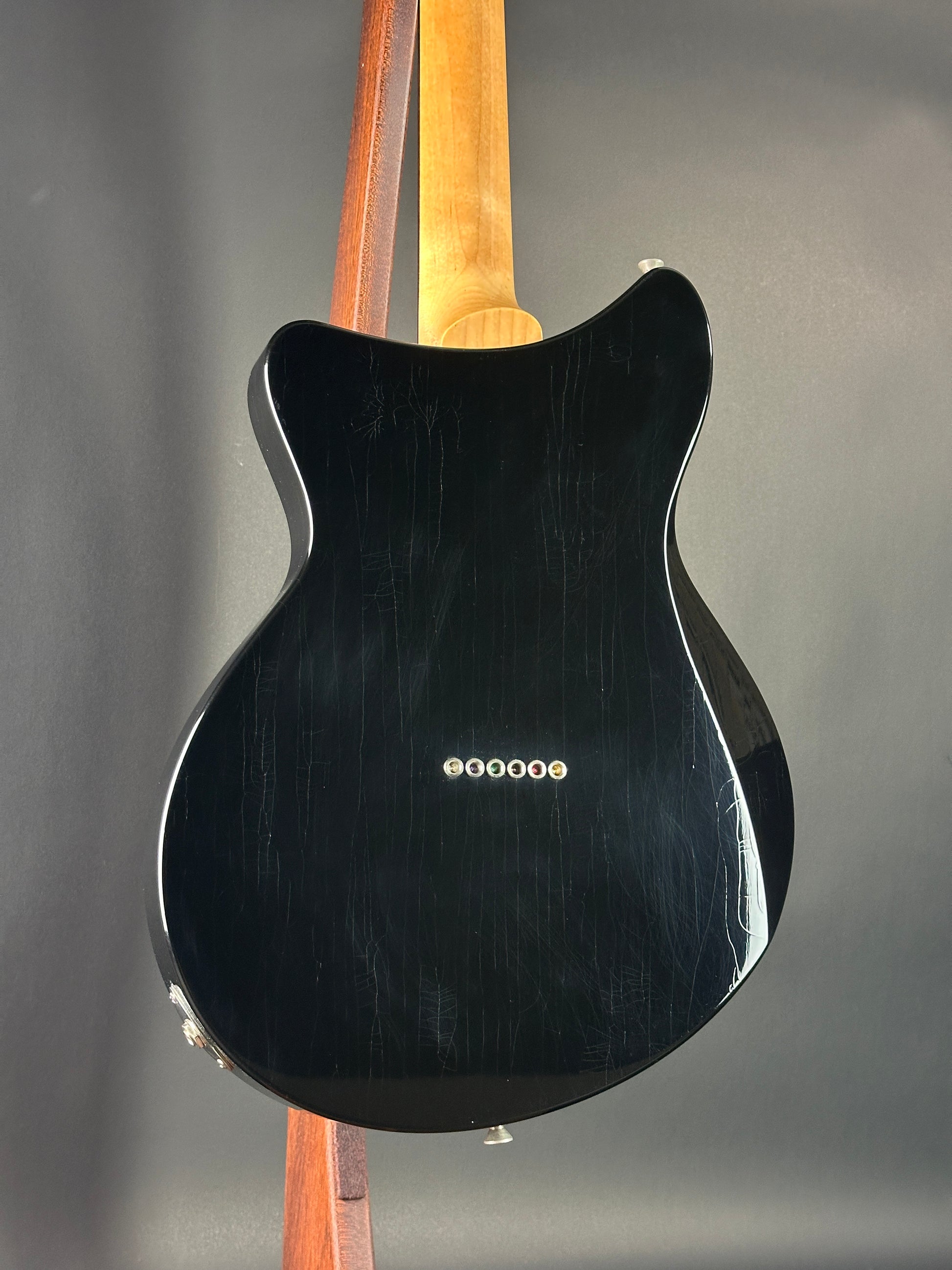 Black electric guitar with a visible brand logo on a gray background