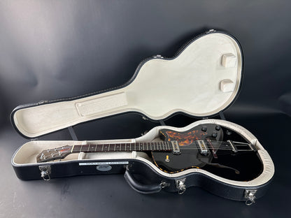 Guitar in an open hardshell case on a dark background