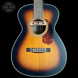 Acoustic guitar with a sunburst finish on a black background, featuring the Tone Shop logo.
