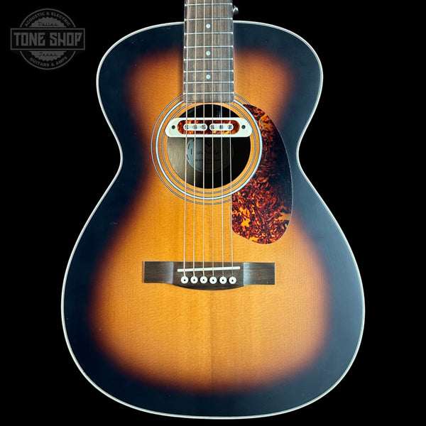 Acoustic guitar with a sunburst finish on a black background, featuring the Tone Shop logo.