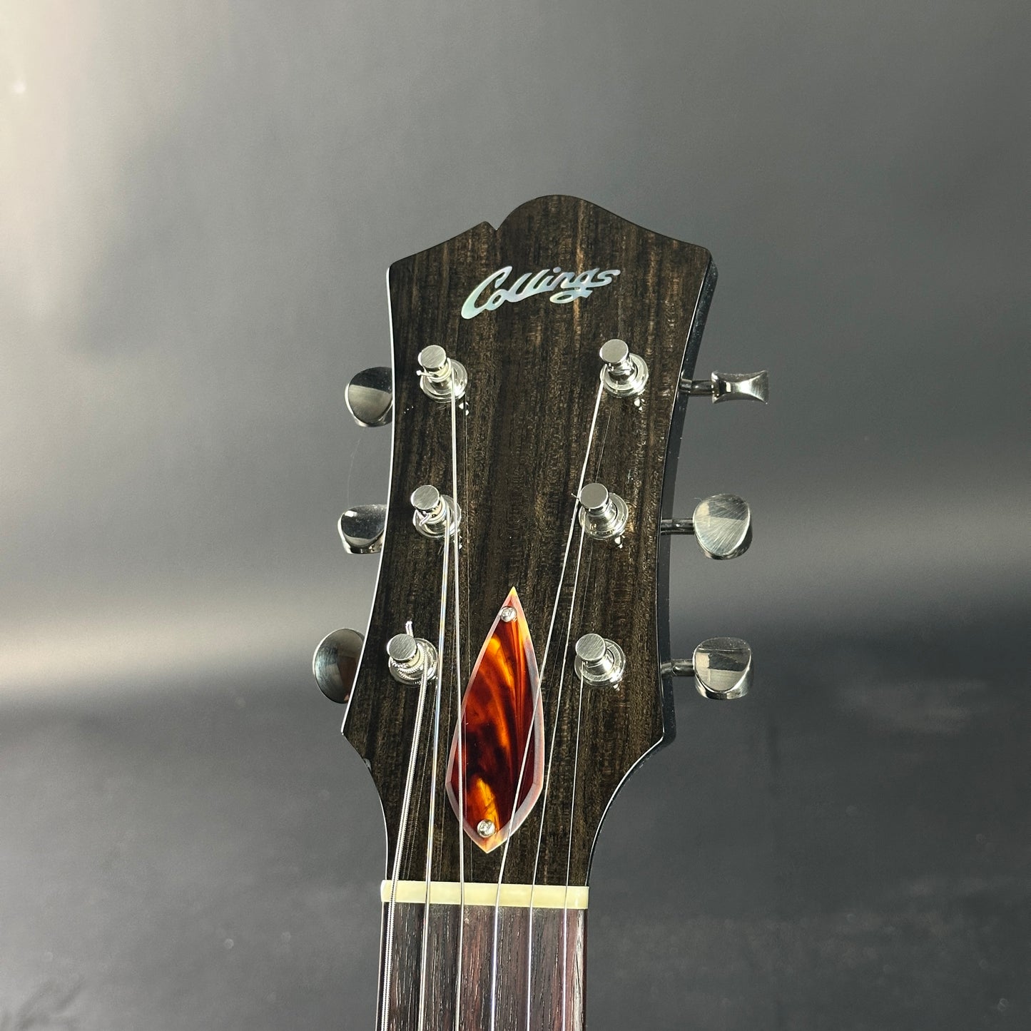 Guitar headstock with 'Collings' logo on a gray background