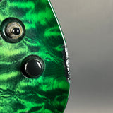 Close-up of the side edge of an electric guitar body featuring a vibrant green flamed maple wood finish with visible wood grain patterns and a black edge trim.