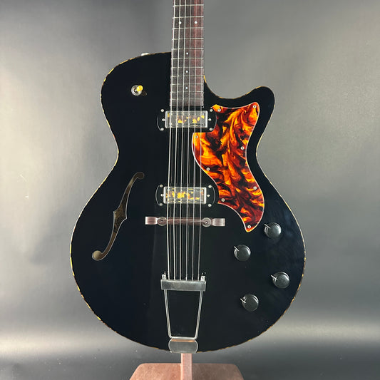 Black electric guitar with a flame pickguard on a gray background