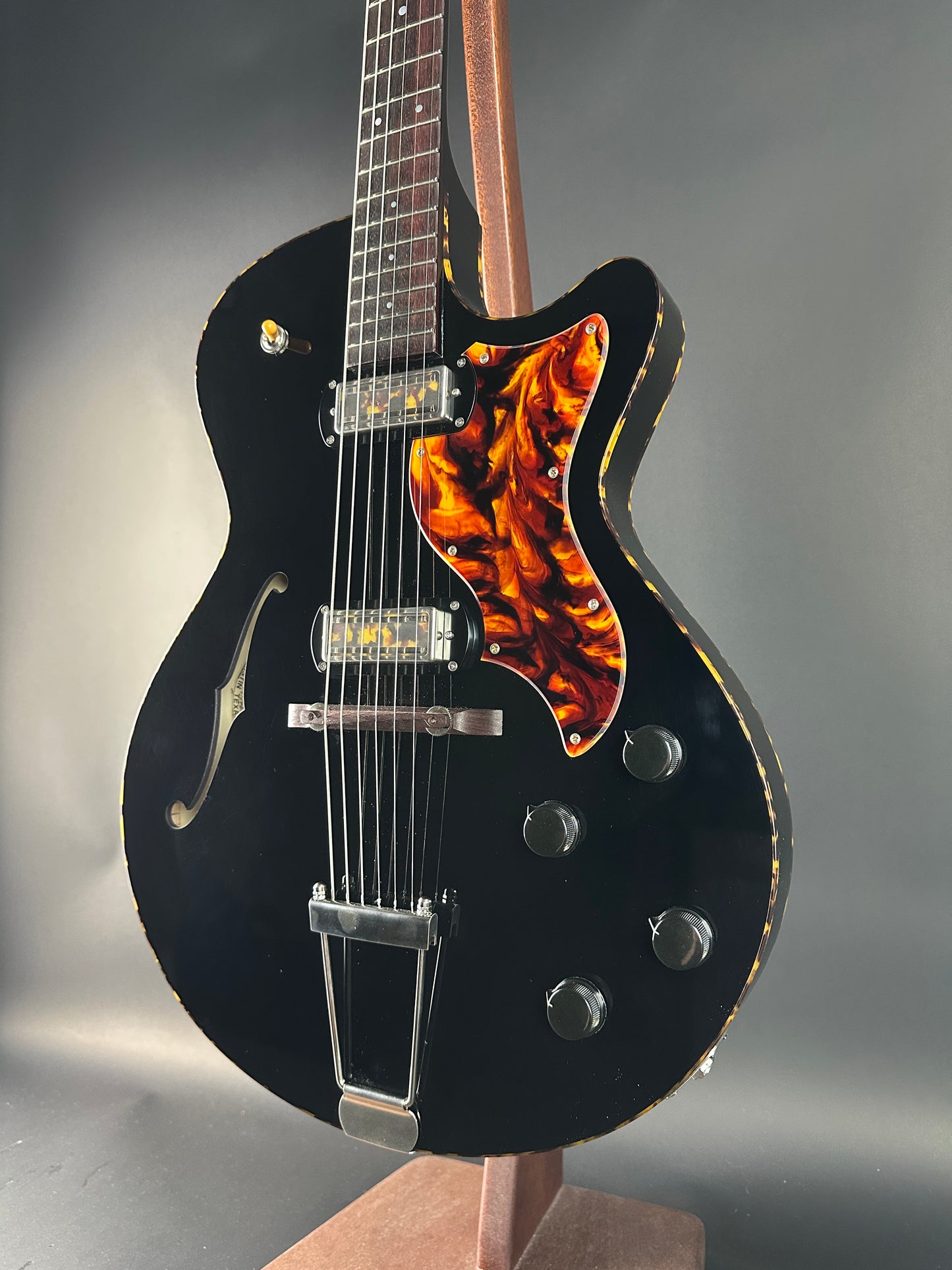 Black electric guitar with flame-patterned headstock on a gray background