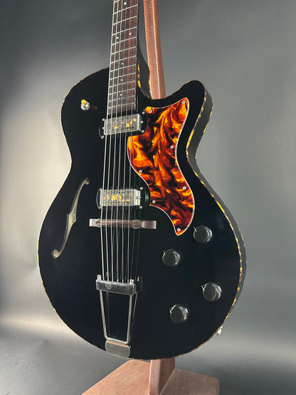 Black electric guitar with flame-patterned headstock on a gray background