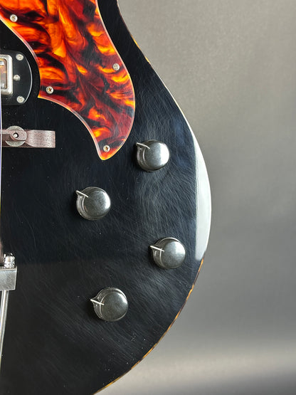 Close-up of a guitar headstock with flame pattern and tuning pegs.