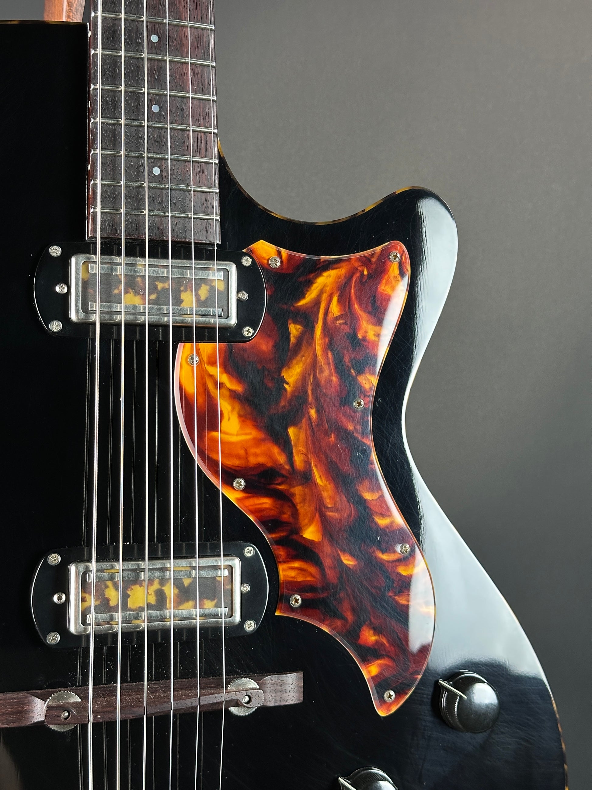 Close-up of a guitar with flame-patterned wood finish on a dark background