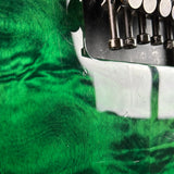 Close-up of a green textured fabric or material with a white curved section and dark metallic hardware visible at the top right.