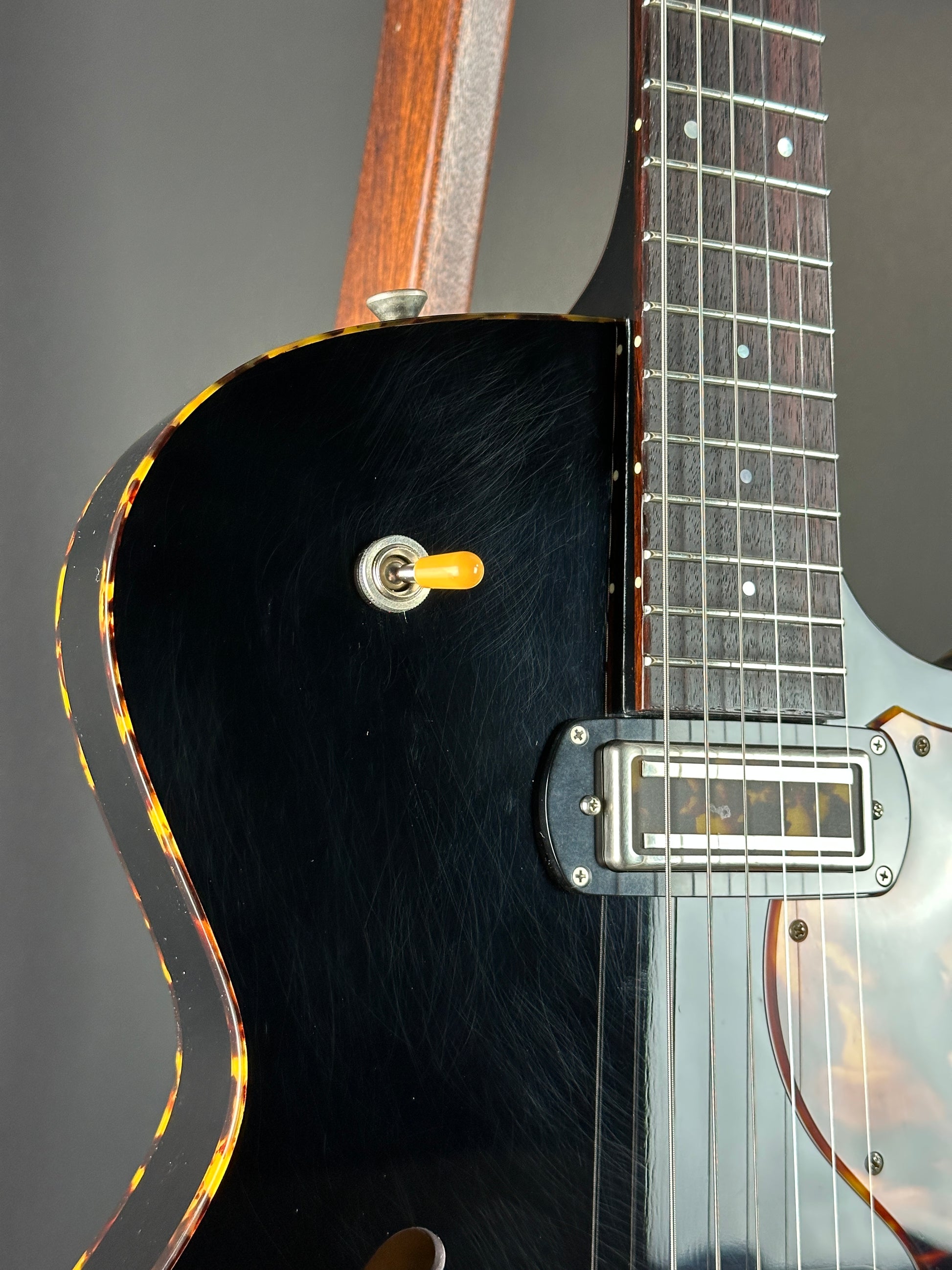 Close-up of a black electric guitar with a focus on the neck and body.