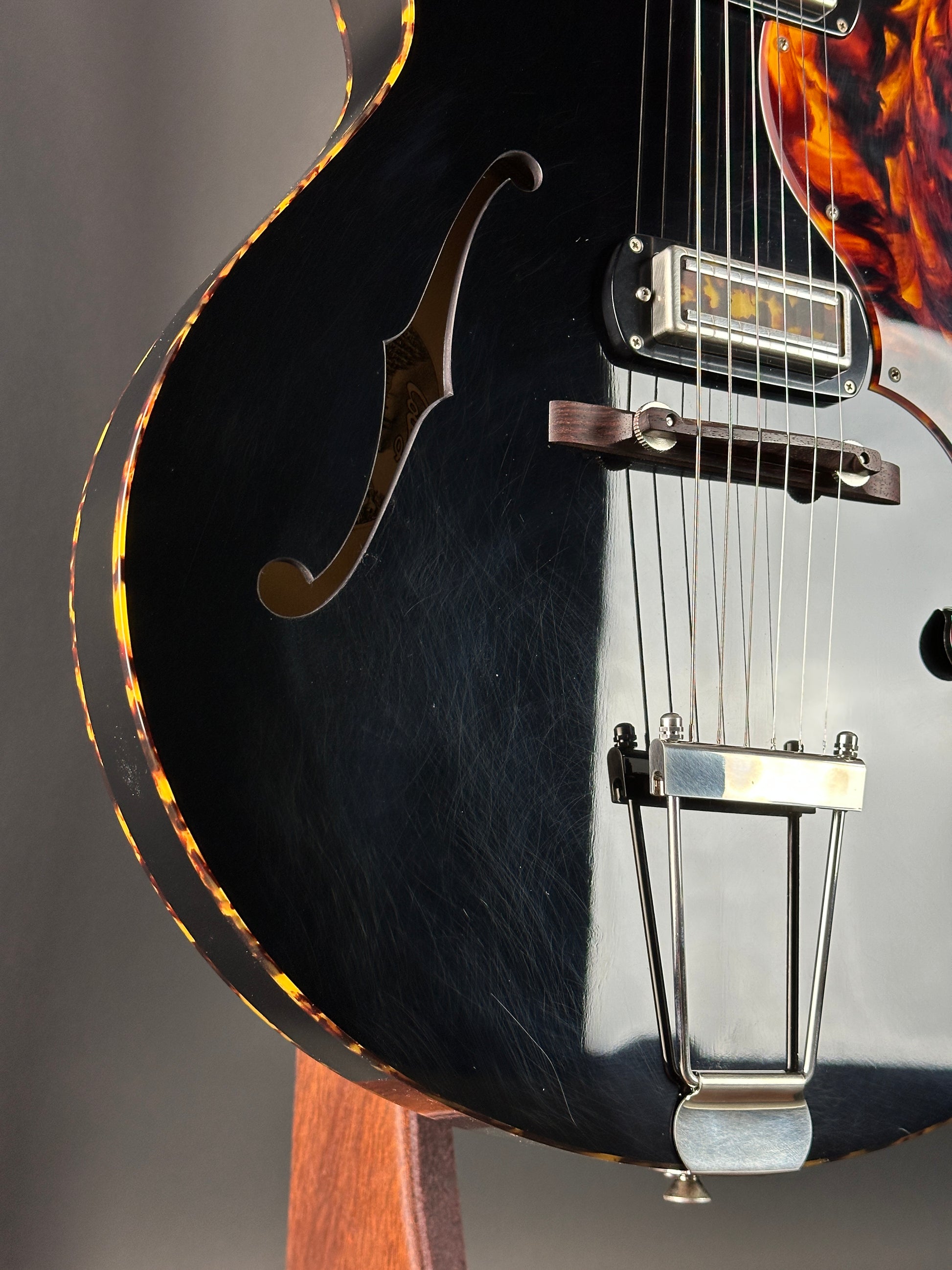 Close-up of a black electric guitar with flame pattern on the body.