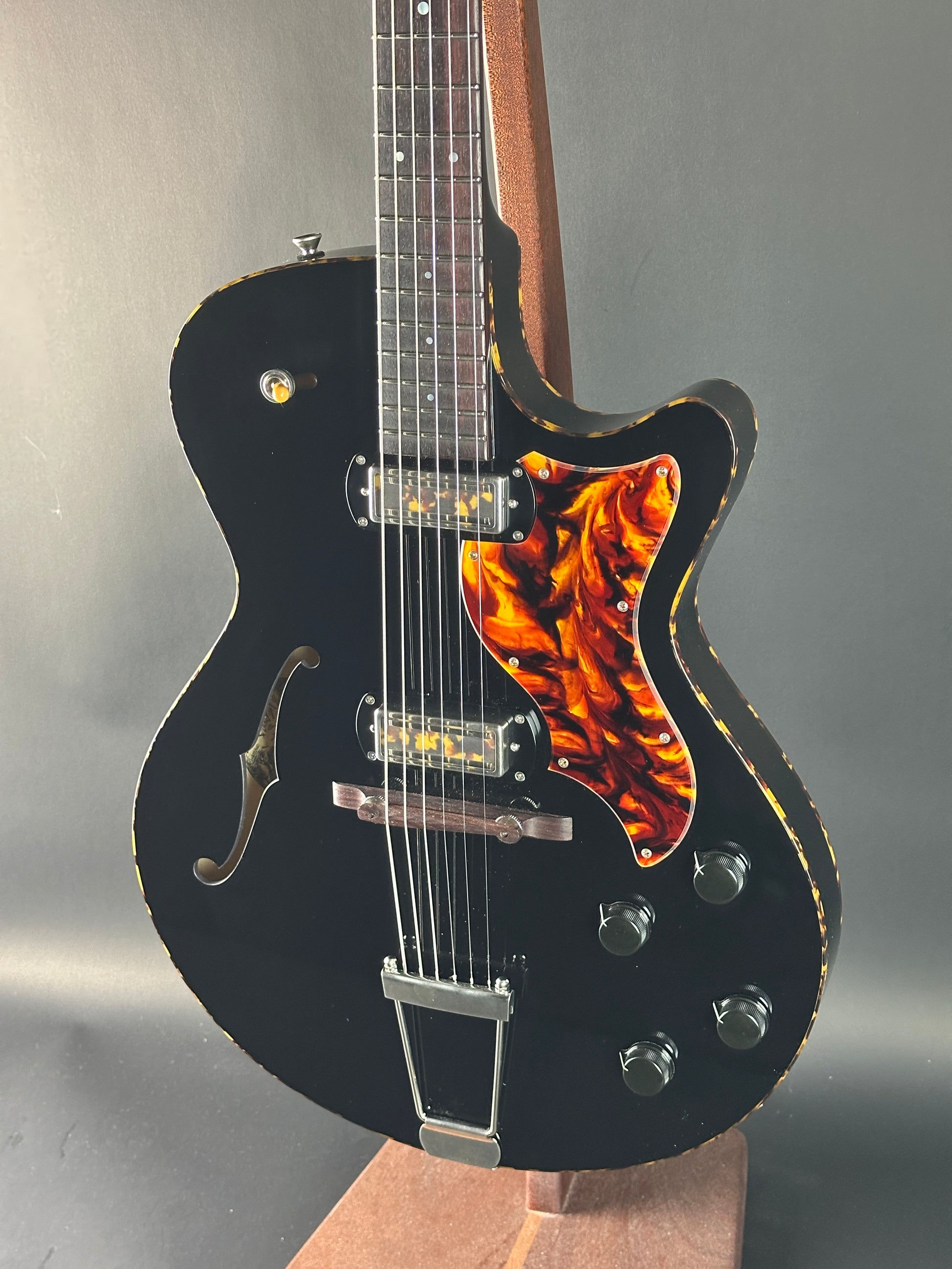 Black electric guitar with flame-patterned body on a gray background