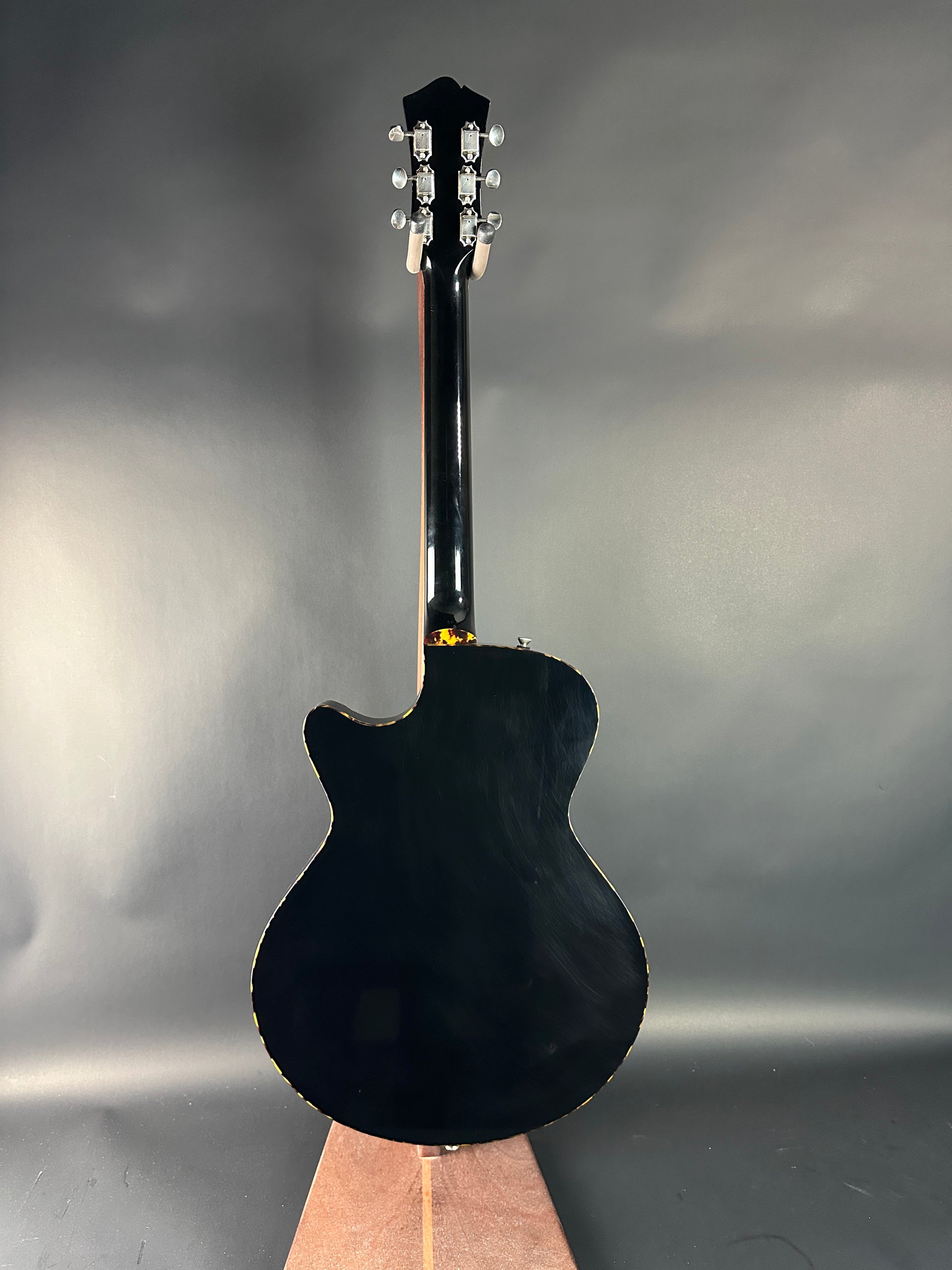 Black electric guitar on a reflective surface with a gray background