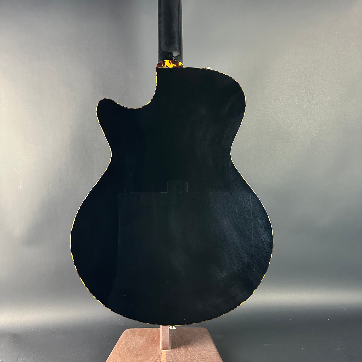 Black electric guitar on a stand against a gray background
