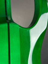Close-up of a bright green guitar body with a glossy finish, showing a cutout opening and a white curved inlay or binding near the top.