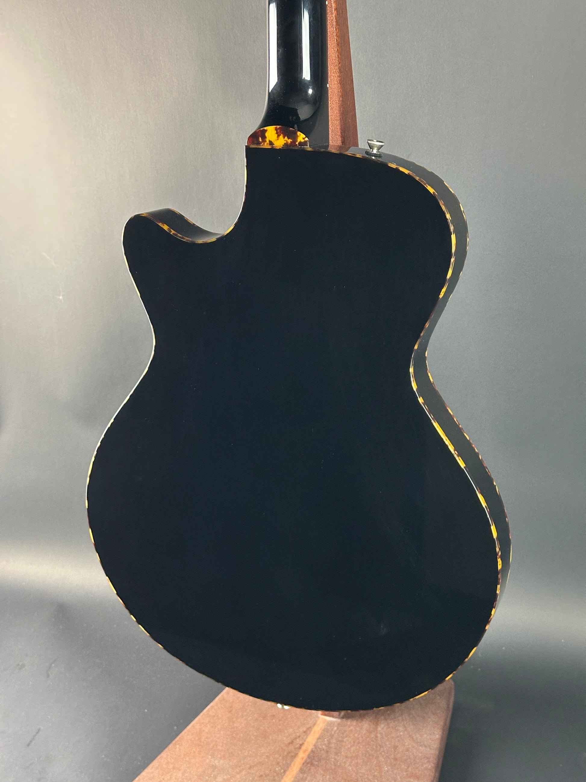 Close-up of a black electric guitar body on a gray background