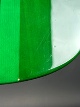 Close-up of a glossy green curved object with a white upper section and a textured green middle band, photographed against a dark gray background.