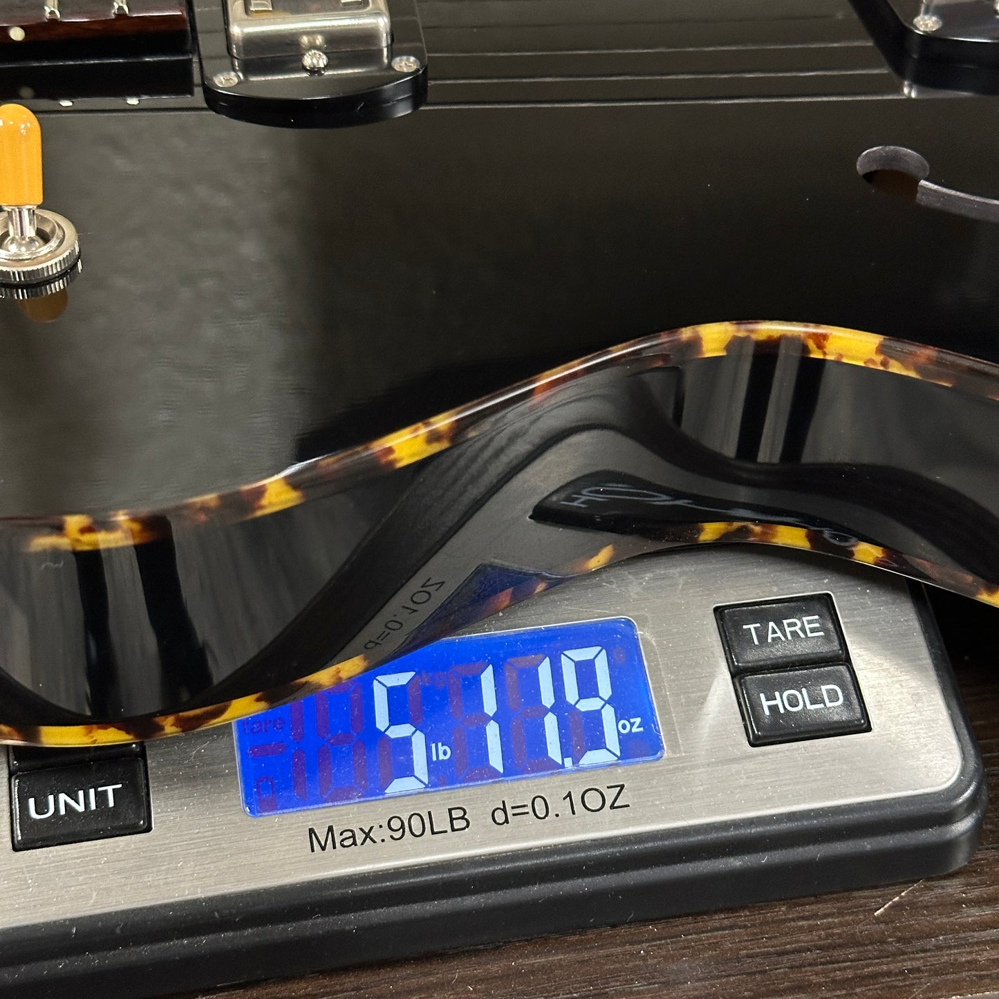 Guitar being weighed on a digital scale with a digital display showing weight.