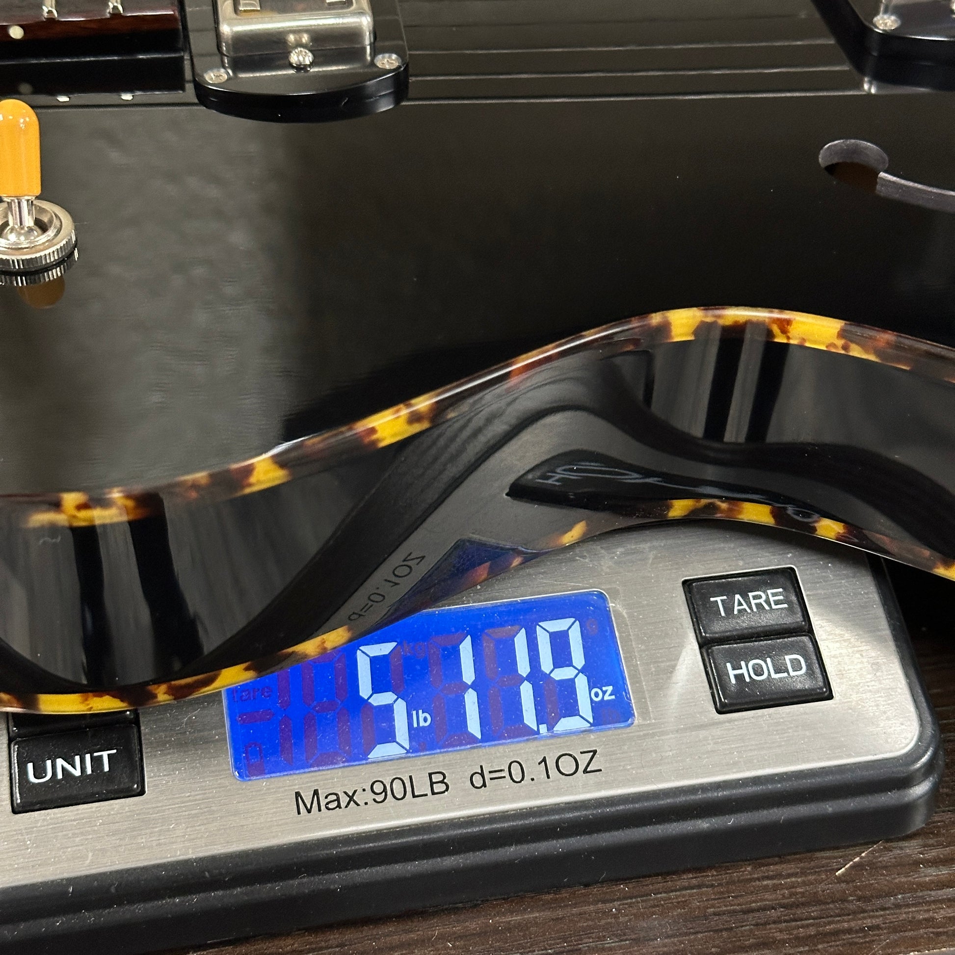 Guitar being weighed on a digital scale with a digital display showing weight.