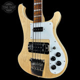 Electric bass guitar with a white pickguard on a black background, featuring the Tone Shop logo.