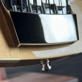 Close-up of a guitar's bridge and tuning pegs on a wooden guitar body.
