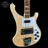 Electric bass guitar with a light wood finish on a black background, featuring the Tone Shop logo.